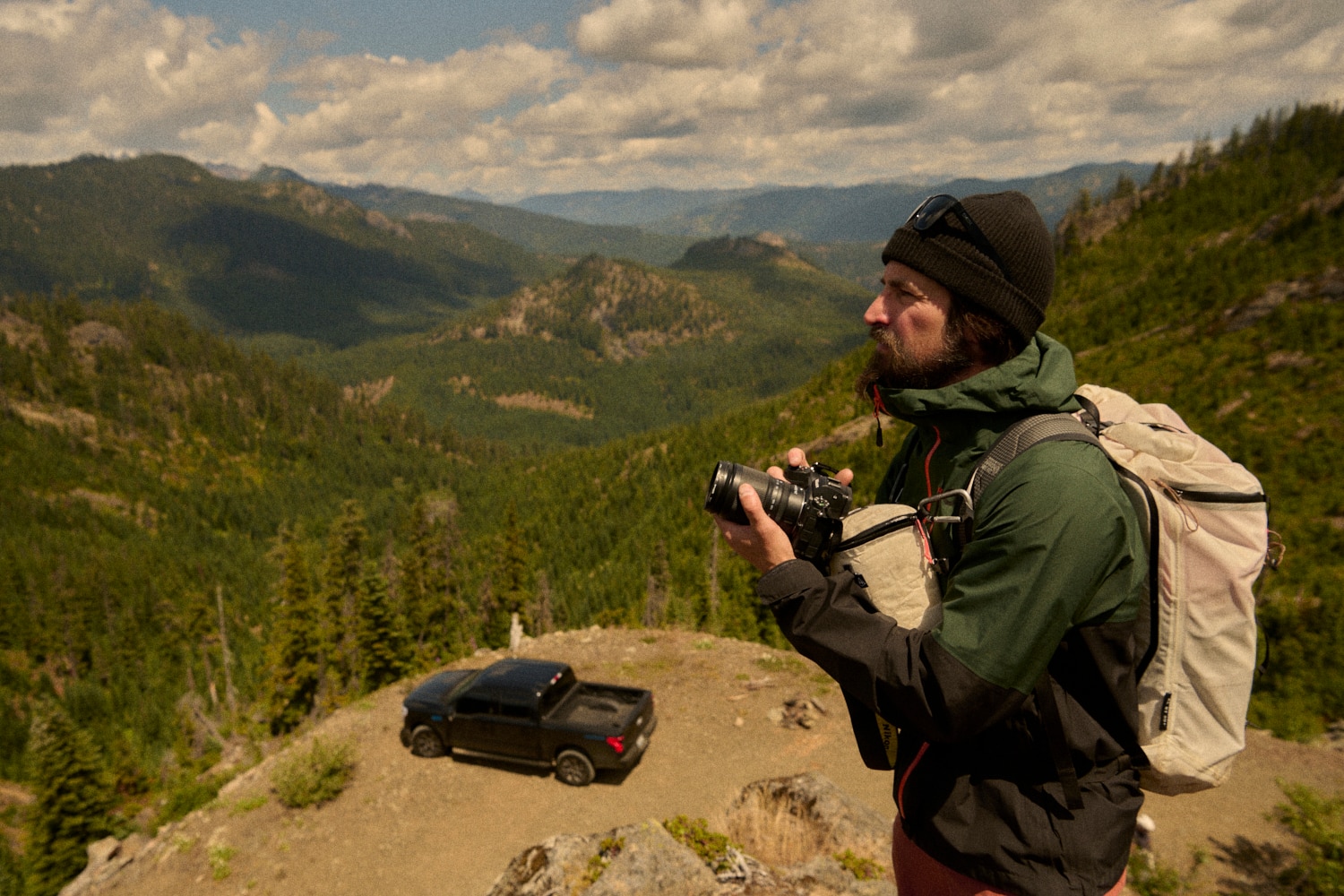 An F-150 Lightning on a gravel mountain road surrounded by tall green trees.